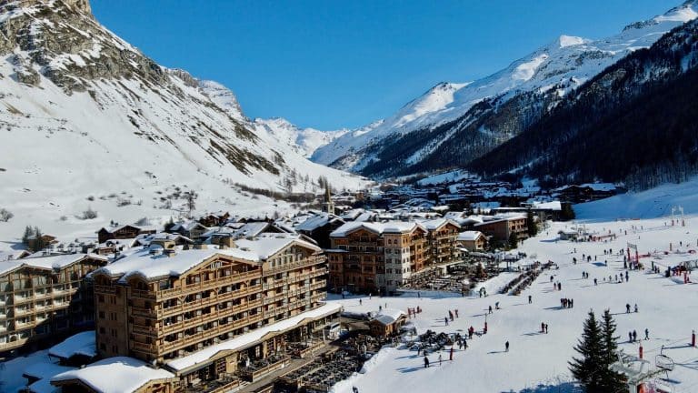 Vue aérienne par drone du centre du village de Val d'Isère dans les Alpes françaises, montrant des hôtels de ski de luxe ski-au-pied, des montagnes enneigées et des pistes de ski.